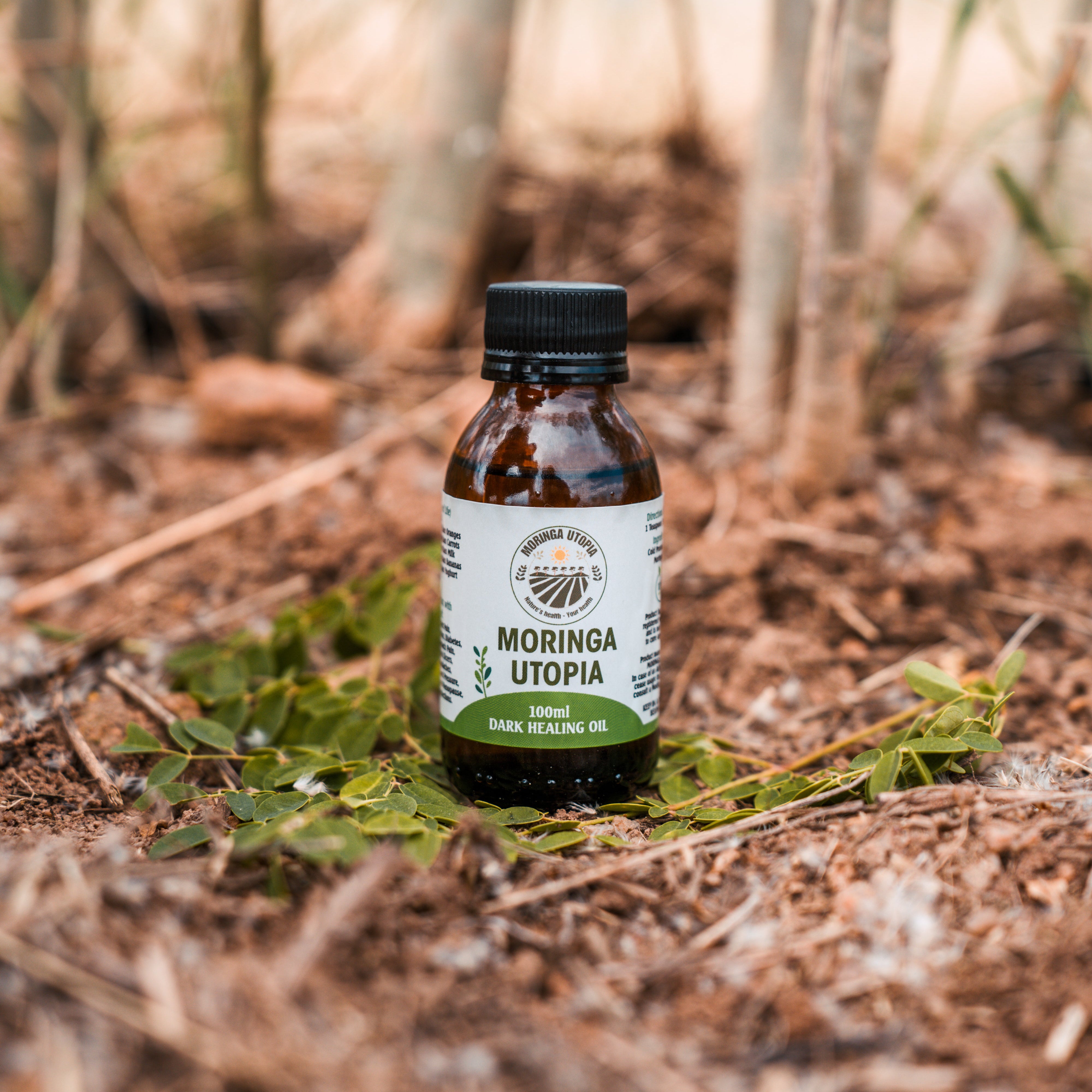 Bottle of Moringa Utopia on a natural background with trees.