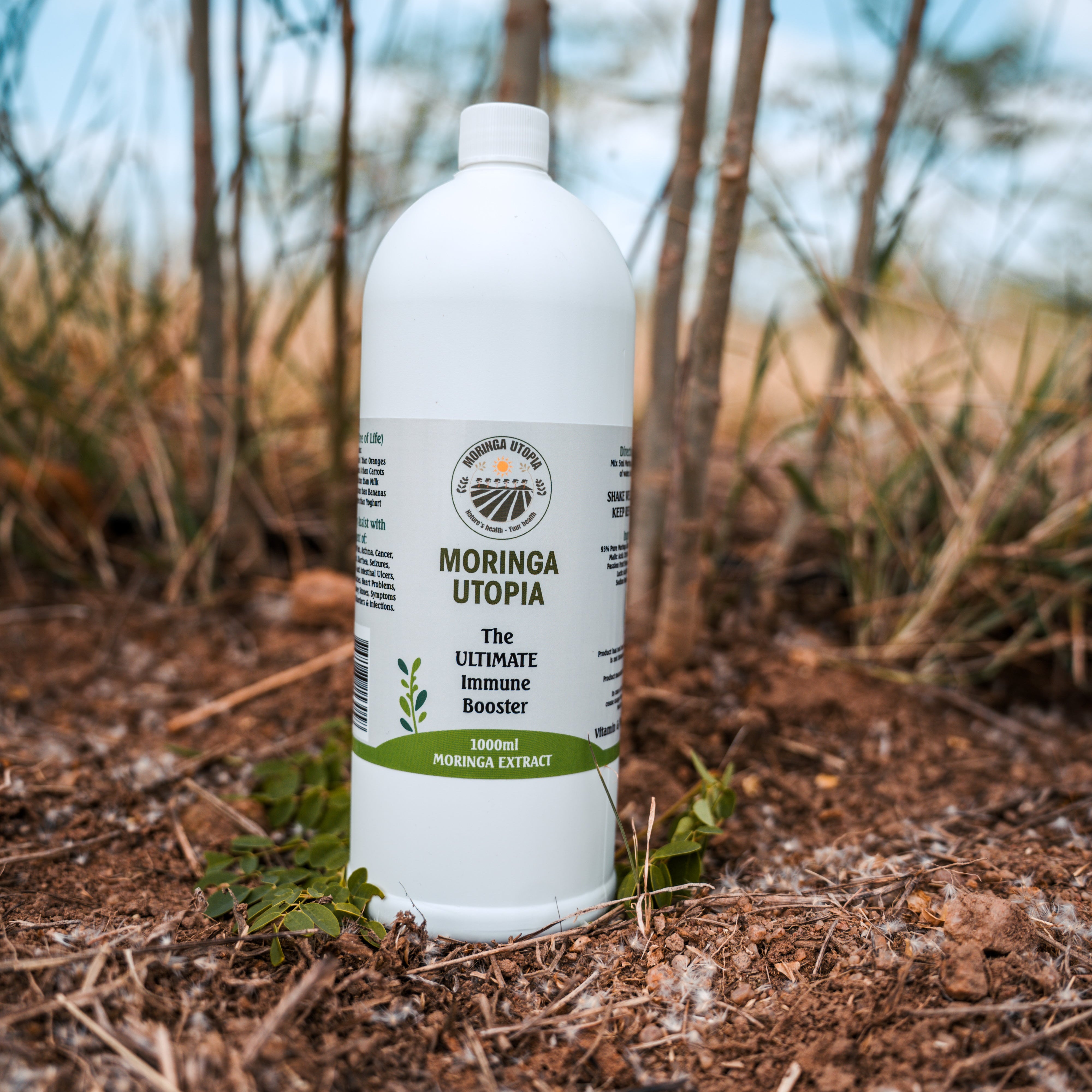 Bottle of Moringa Utopia product on a natural background with trees and plants.