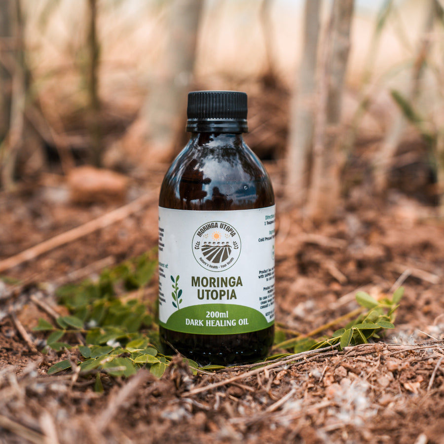 Bottle of Moringa Utopia dark oil in a forest setting